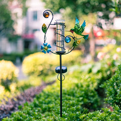 Stargarden Hummingbird Rain Gauge illuminated at night in the garden