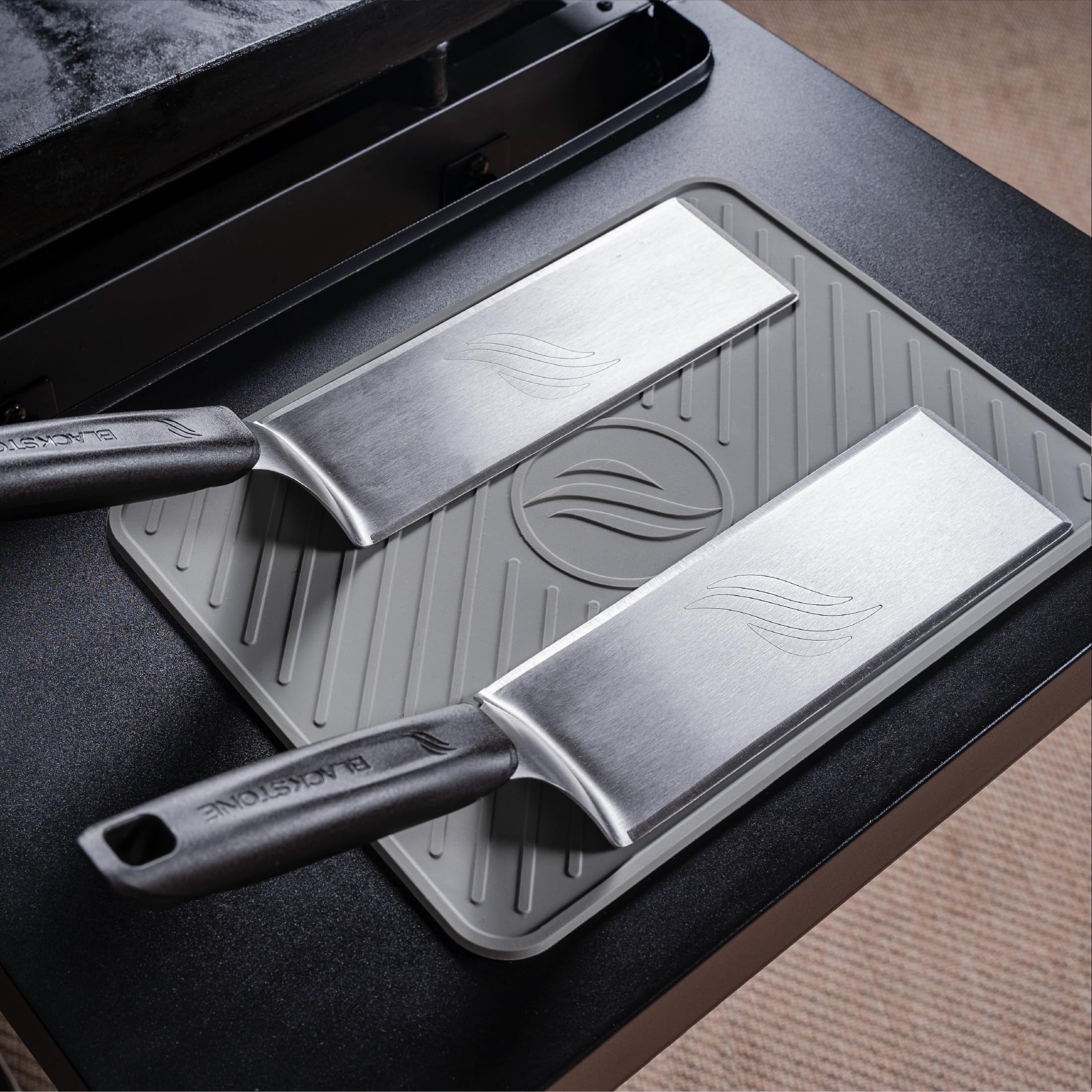 BLACKSTONE spatula mat resting on a grill shelf with tools