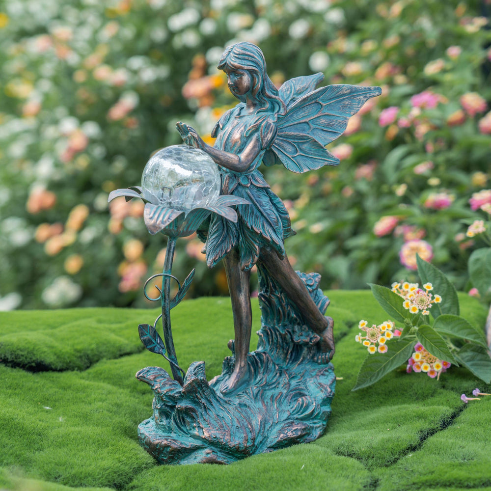 Bronze fairy statue illuminated at night in a garden