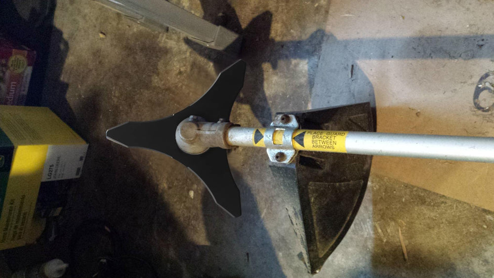 Eapele brush cutter blade next to dense grass and bushes