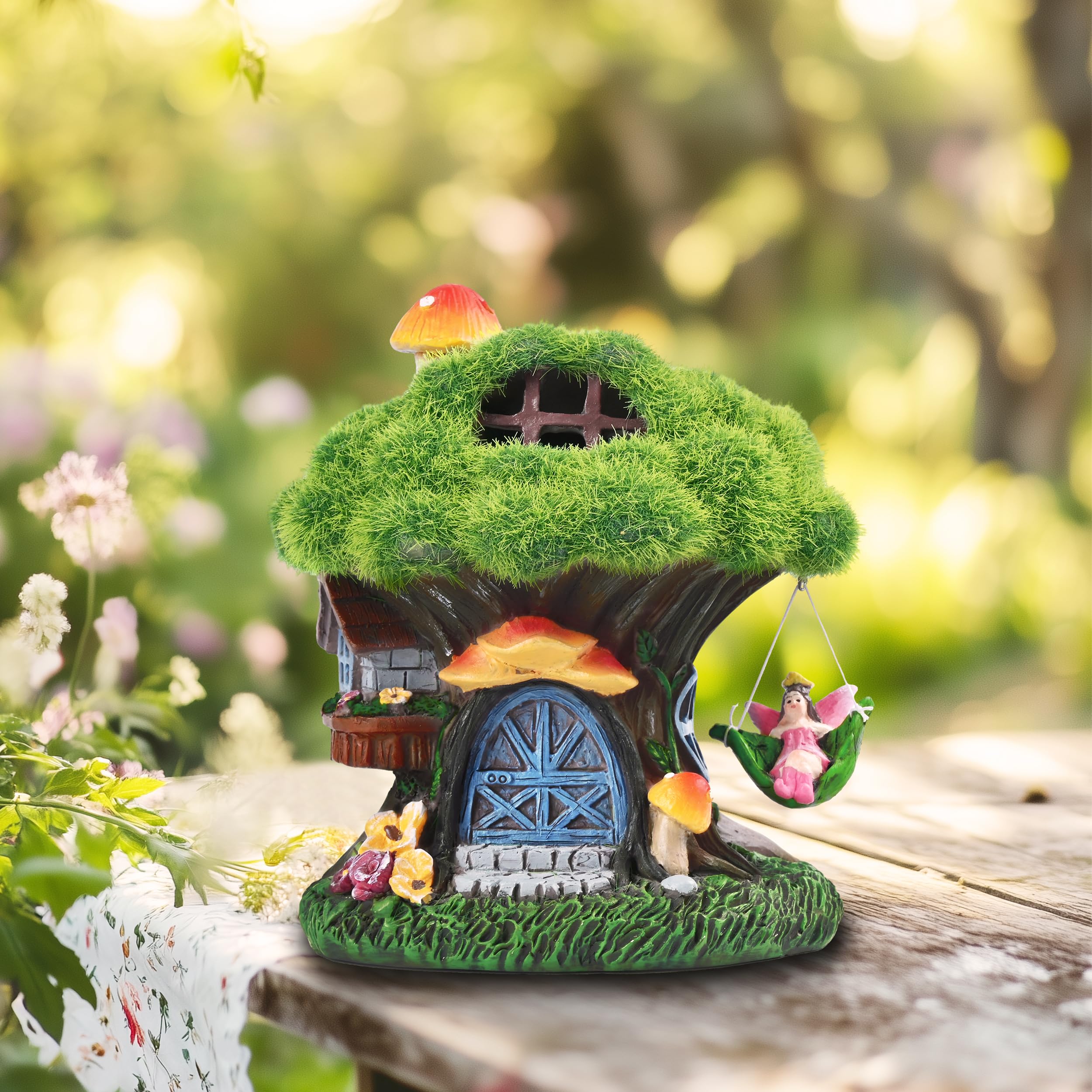 Fairy house statue next to potted plants on a patio