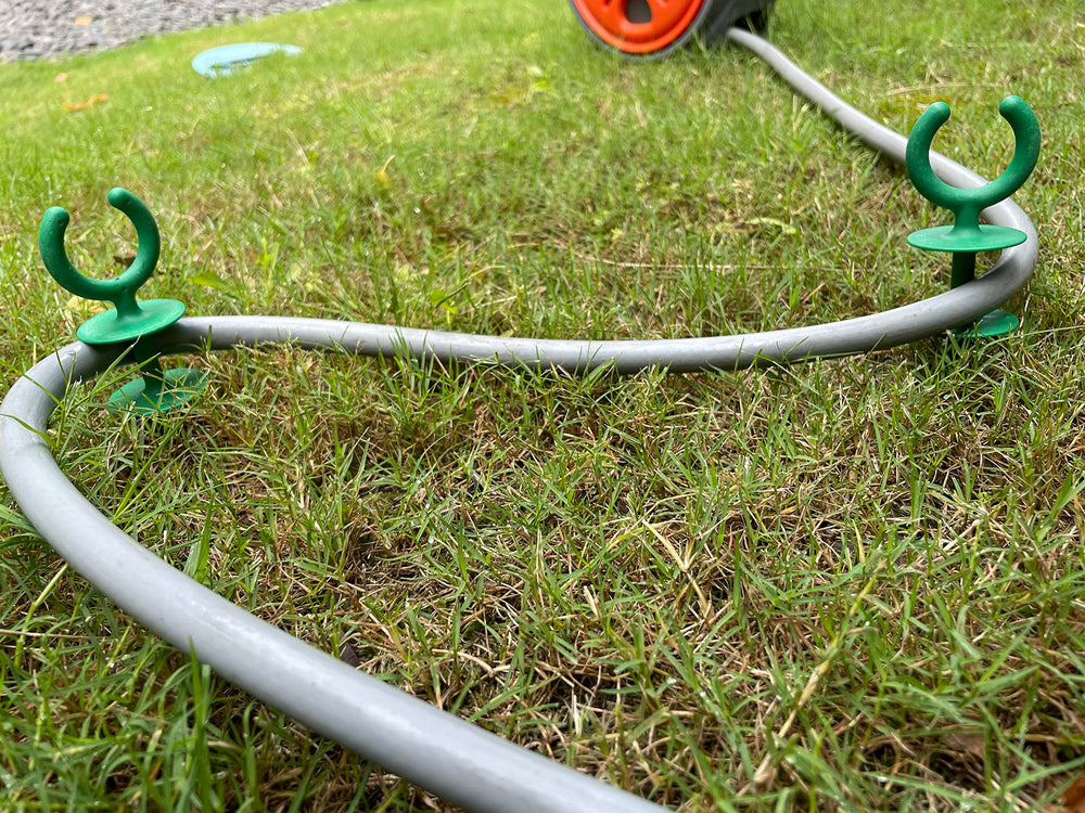 Garden hose guide stakes protecting plants