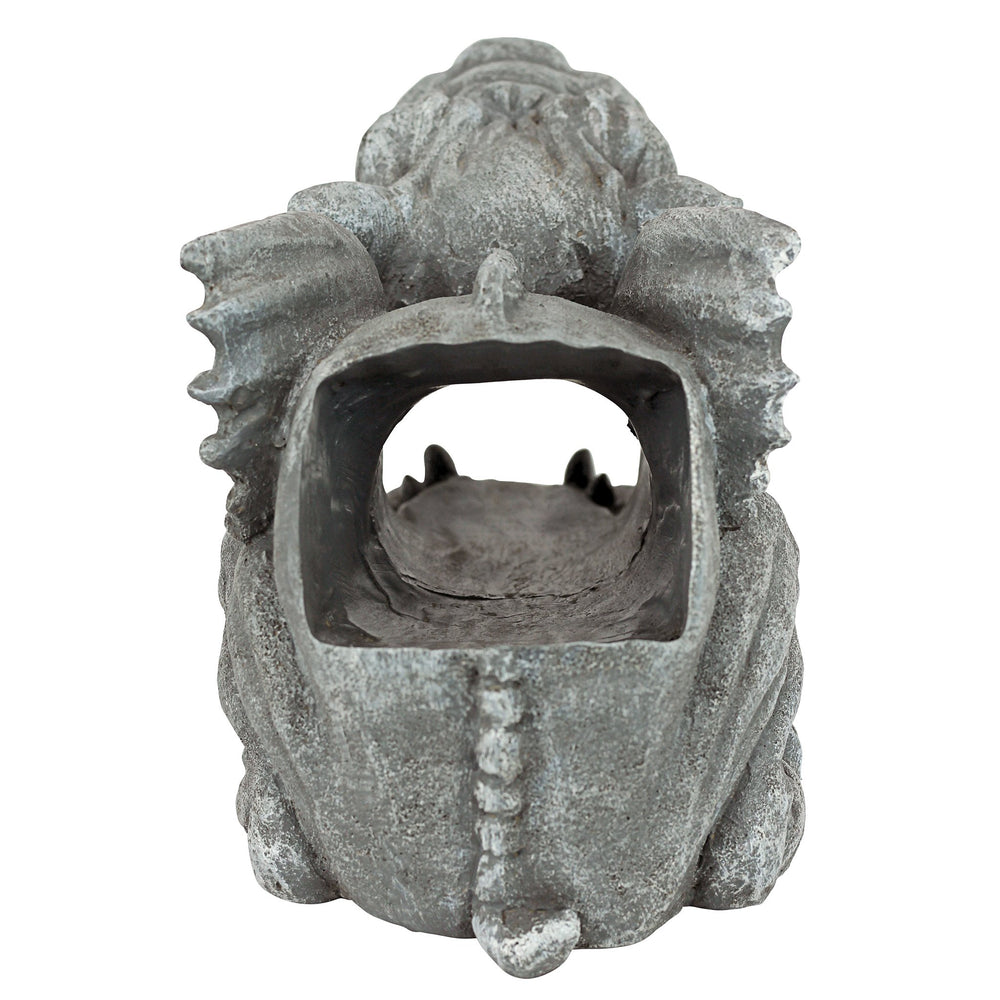 Gargoyle positioned on a downspout in a garden