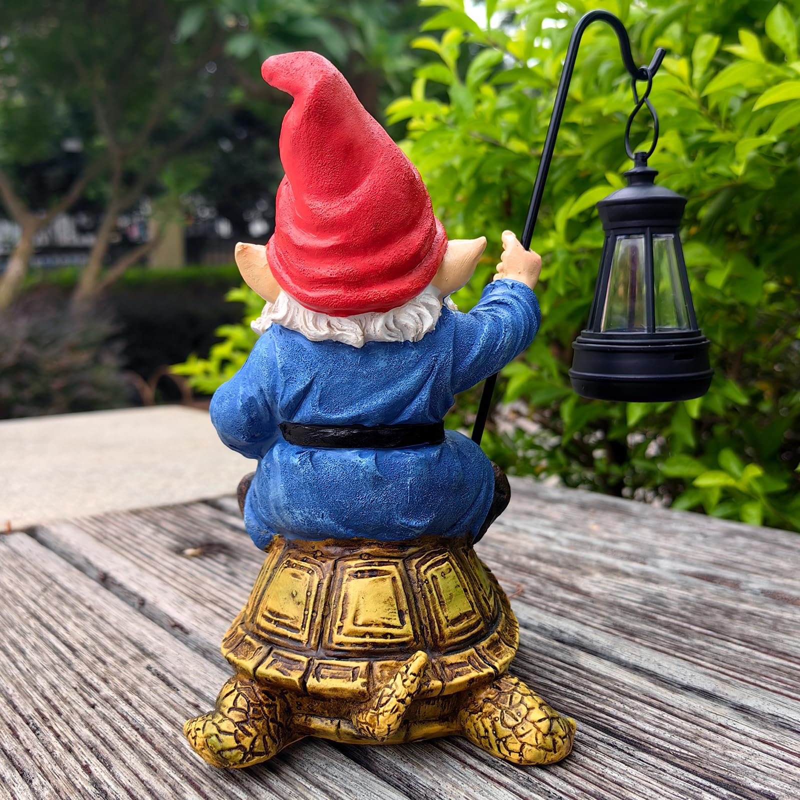 Gnome riding turtle statue with greenery background