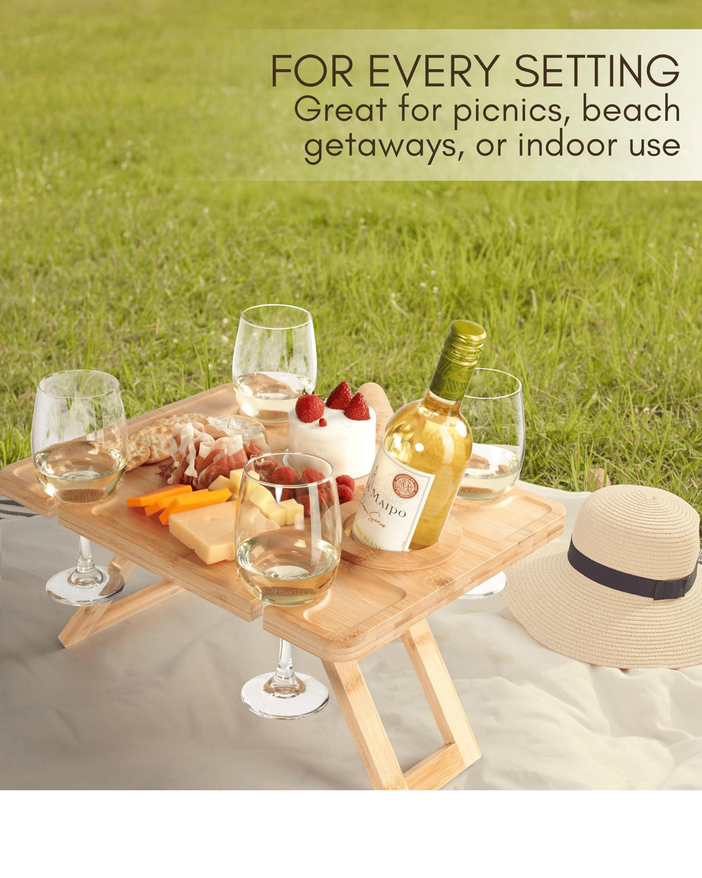 Light brown bamboo picnic table set up with wine glasses and snacks