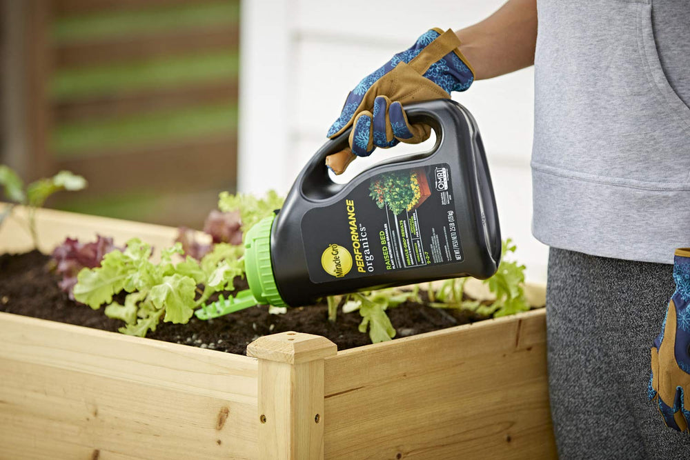 Miracle-Gro Performance Organics granules being applied to a raised garden bed