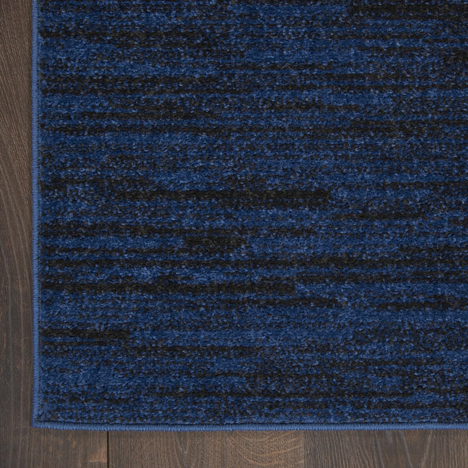 Nourison Essentials Midnight Blue Area Rug layered with patterned rug