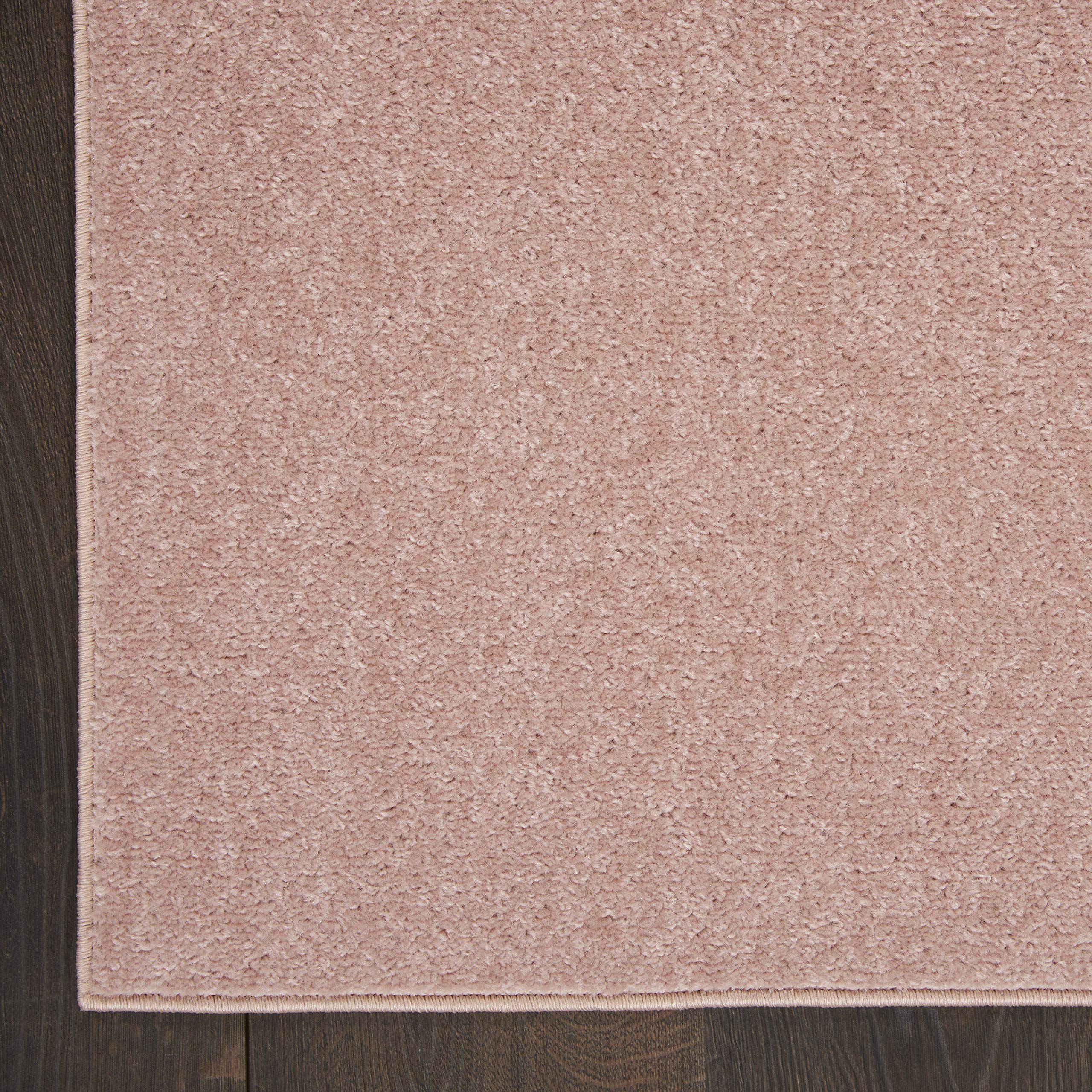 Nourison Essentials Pink Outdoor Rug layered with patterned rugs