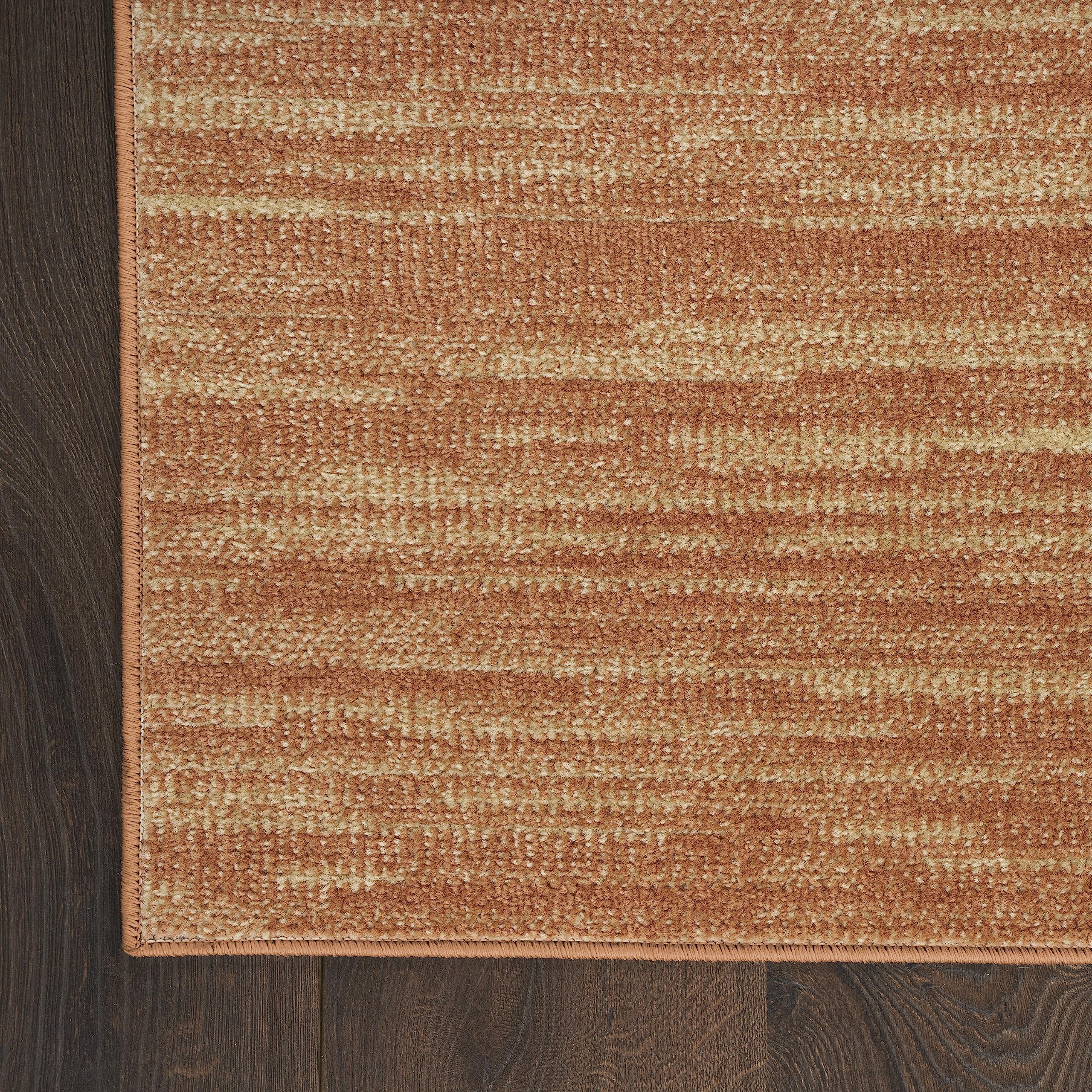 Nourison Essentials Rust Outdoor Rug layered with patterned rug
