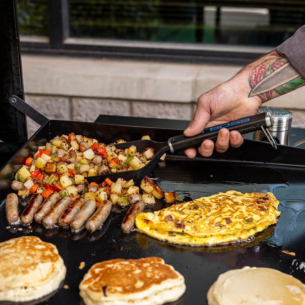 PIT BOSS Griddle Grub Shovel on a griddle with burgers and hashbrowns