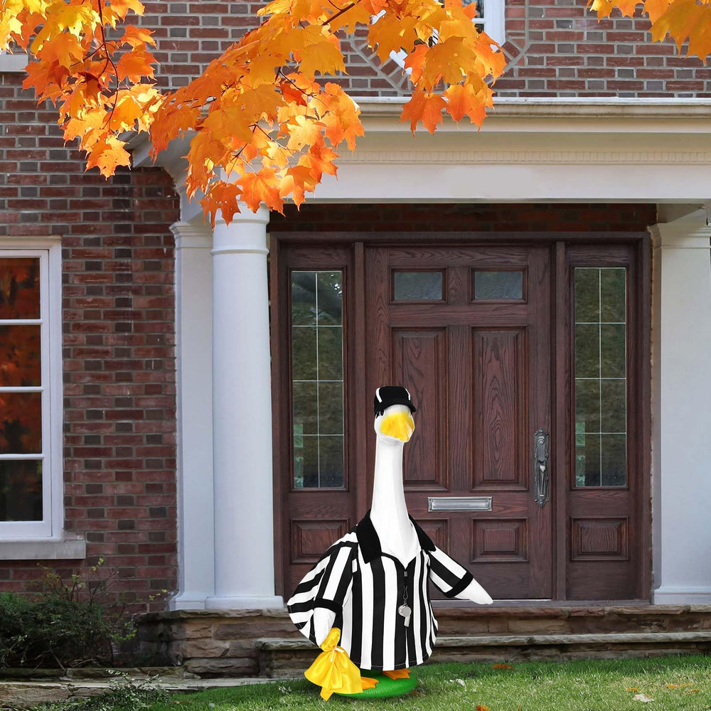 Referee goose outfit on a lawn goose statue in a garden