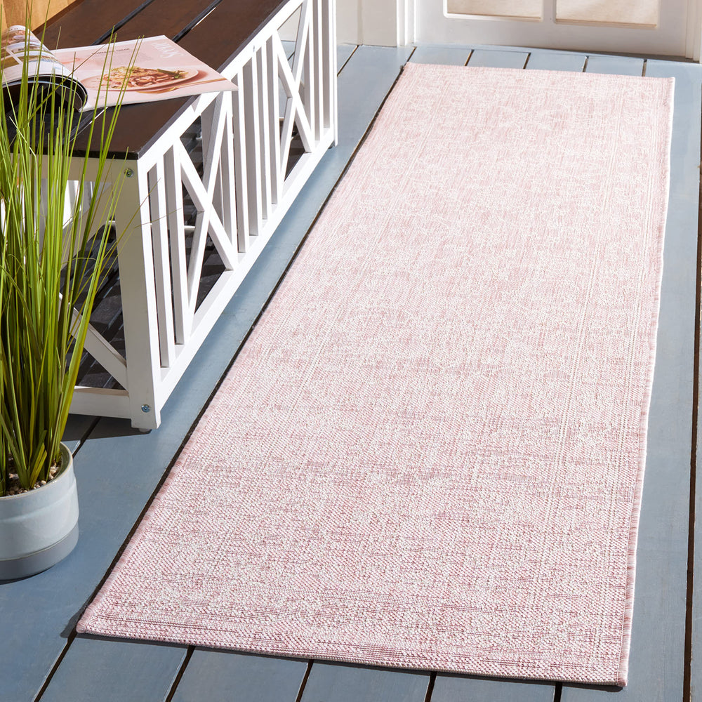 SAFAVIEH runner mat being rinsed with a garden hose