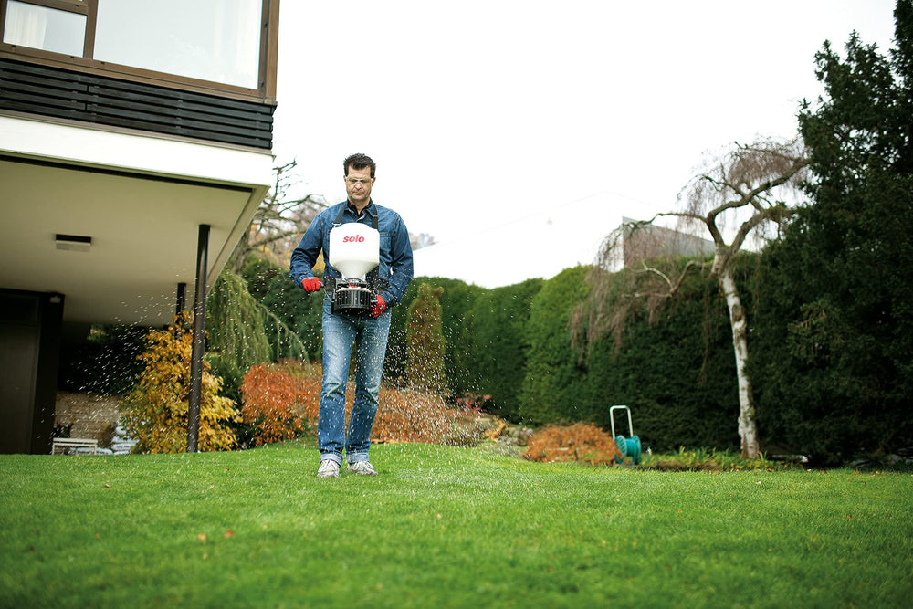 SOLO spreader in a garden setting with grass seed being spread