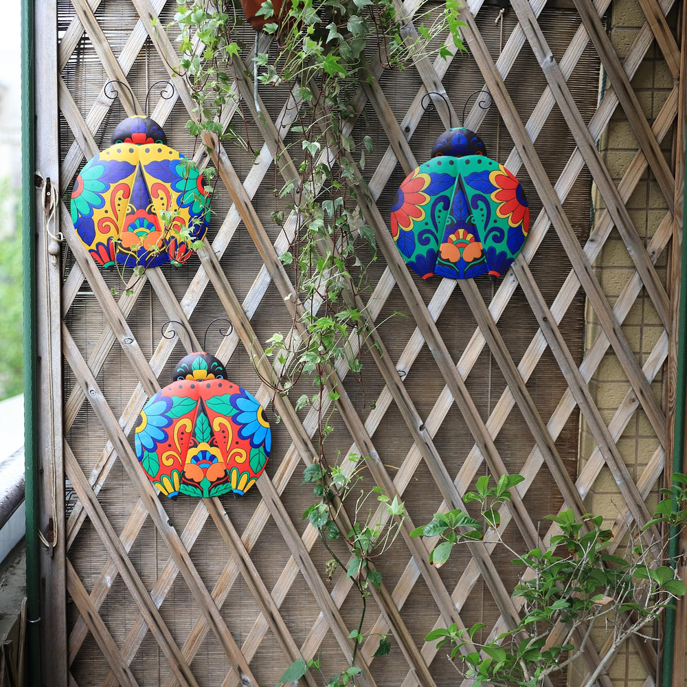 Three pieces of Scwhousi Metal Ladybugs Wall Decor hanging on a garden wall