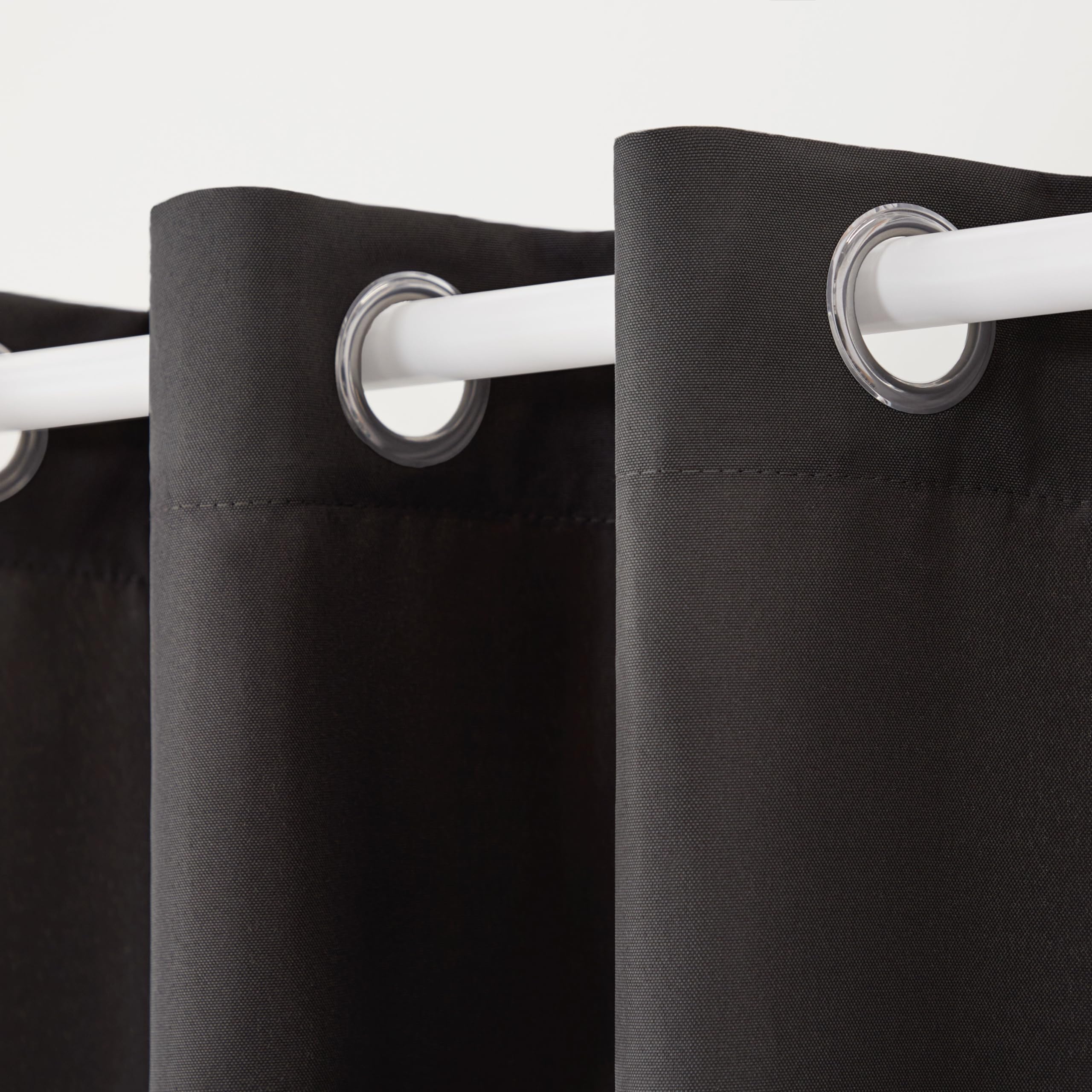 Two panels of TOWN & COUNTRY BASICS Cabana Solid Heavyweight Curtains hanging on a patio