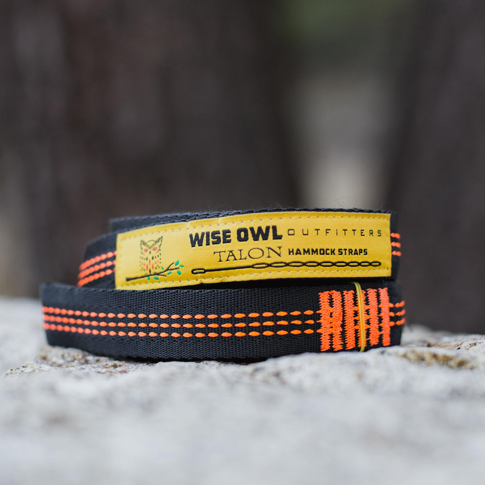 Two Wise Owl hammock straps with carabiners laid out on grass