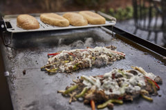 Weber Griddle Keep Warm Rack in use at a barbecue