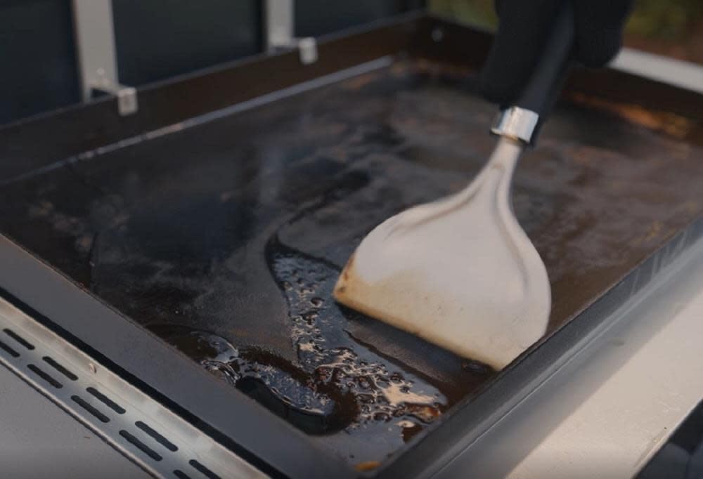 Weber Griddle Scraper in use on a griddle