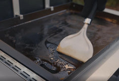 Weber Griddle Scraper in use on a griddle